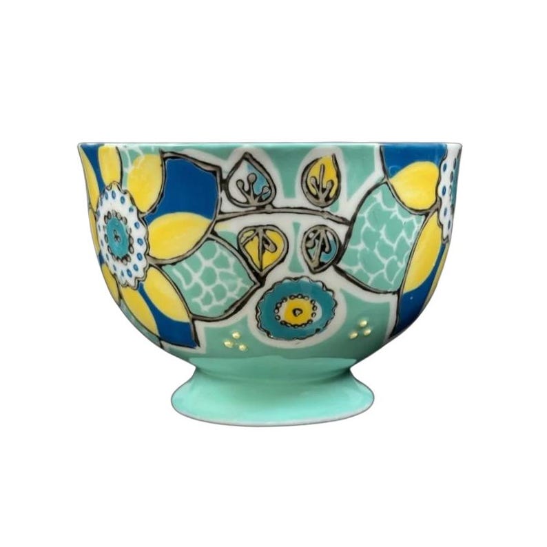 Anthropologie Elka Ayaka green floral pedestal mug with turquoise base and bold yellow and blue flower motifs