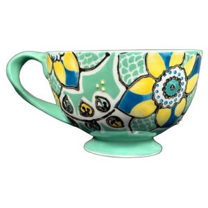 Anthropologie Elka Ayaka green floral pedestal mug with yellow and blue flower pattern on mint base