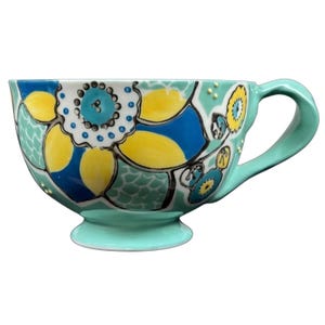 Anthropologie Elka Ayaka green floral pedestal mug with turquoise handle and yellow blue hand painted flowers