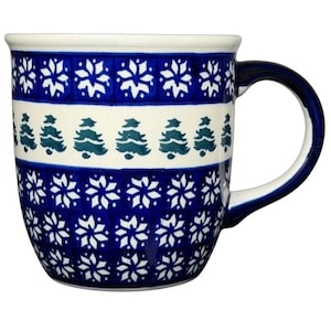 May include: A ceramic mug with a dark blue and white snowflake and Christmas tree pattern. The mug has a white interior and a dark blue handle. The design features alternating bands of snowflakes and Christmas trees.
