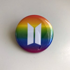 May include: A round button with a rainbow background and a white "BTS" logo in the center.