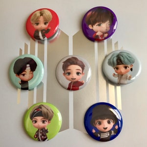 May include: Seven round buttons with cartoon illustrations of people. The buttons are in various colors, including red, blue, green, purple, and light blue. Each button features a different cartoon character with a unique expression and pose.