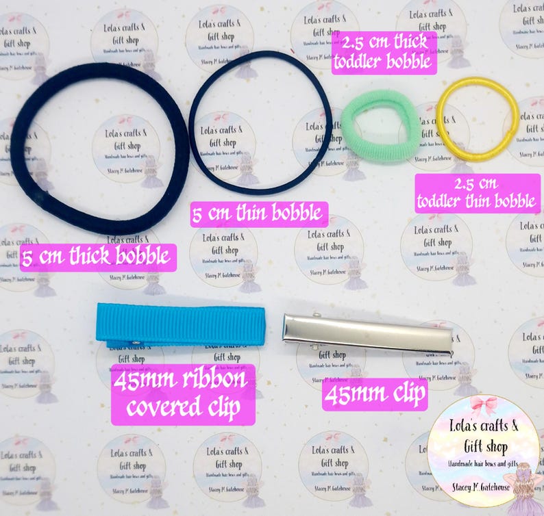 May include: Assortment of hair accessories including black and navy blue bobbles, a light blue ribbon-covered clip, a silver clip, and green and yellow toddler bobbles. The image also includes text that reads "Lola's crafts & gift shop".