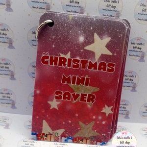 May include: A stack of Christmas Mini Saver tags with a red and white gradient background. The tags feature gold stars and the words "CHRISTMAS MINI SAVER" in red. A silver ring holds the tags together.