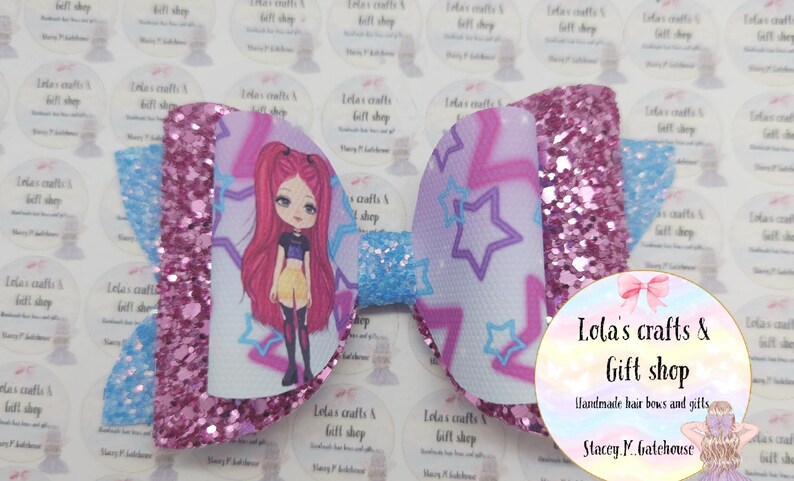 May include: A large, decorative hair bow featuring a cartoon girl design. The bow has a glittery pink center and edges, with a light blue center and wings. The bow has a white background with purple stars and a cartoon girl. The bow is from Lola's Crafts & Gift Shop.