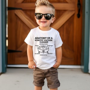 May include: A white t-shirt with a black illustration of a robotic vacuum cleaner and the text "Anatomy of a Robotic Vacuum Cleaner". The illustration shows the different parts of the vacuum cleaner, including the infrared sensor, handle, bin release, side brush, and power button.