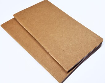 May include: Two brown notebooks with stitched binding. The notebooks are stacked on top of each other.