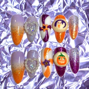 May include: Set of ten Halloween-themed fake nails with various designs. The nails are decorated with orange, purple, white, and glitter. Some nails feature 3D embellishments, including a heart, a star, a ghost, a pumpkin, and a candy cane.