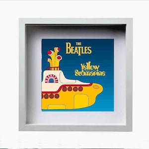 May include: Framed artwork featuring the Beatles' "Yellow Submarine" album cover. The image shows a yellow submarine with red and brown details against a blue background. The Beatles' logo is at the top.