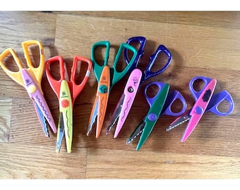Puede incluir: Un conjunto de seis pares de tijeras de manualidades con hojas decorativas para cortar bordes con patrones. Las tijeras cuentan con mangos en varios colores, incluyendo amarillo, naranja, verde, morado y rosa, con hojas de metal.