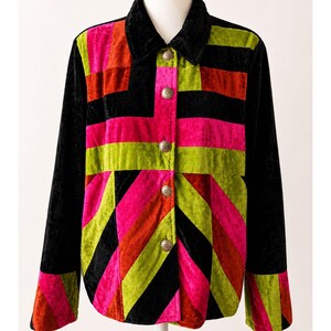 May include: A long-sleeved jacket featuring a vibrant patchwork design of velvet panels in black, hot pink, lime green, and burnt orange. The garment includes a black collar, a front button closure with four circular silver-toned metal buttons.