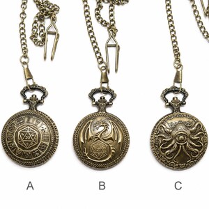 K&ouml;nnte beinhalten: Drei Taschenuhren in Antik-Bronze-Optik mit Ketten und Clips. Uhr A zeigt einen 20-seitigen W&uuml;rfel umgeben von Tierkreiszeichen. Uhr B zeigt einen Drachen mit einem 20-seitigen W&uuml;rfel. Uhr C zeigt ein tentakelartiges Wesen mit einem zentralen Auge.