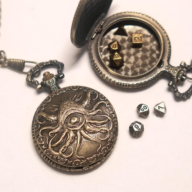 K&ouml;nnte beinhalten: Zwei Taschenuhrgeh&auml;use aus Bronze im Antik-Stil mit detaillierten Gravuren von einem Oktopus und einem Auge. Ein Geh&auml;use ist geschlossen, das andere ist ge&ouml;ffnet und zeigt ein strukturiertes Inneres mit kleinen polyedrischen Metallw&uuml;rfeln.