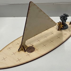 May include: A wooden miniature ship model with a sail, a figure of a space marine, and a flag. The ship is on a base with a rope design.