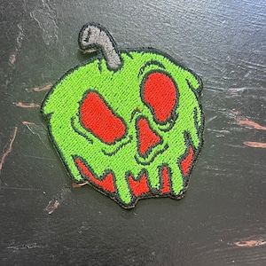 May include: Green embroidered apple patch with a red, dripping, skull-like face.