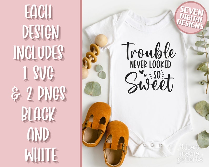 May include: White baby onesie with black text that reads "Trouble never looked so sweet". The onesie is on a white background with brown shoes and green leaves.
