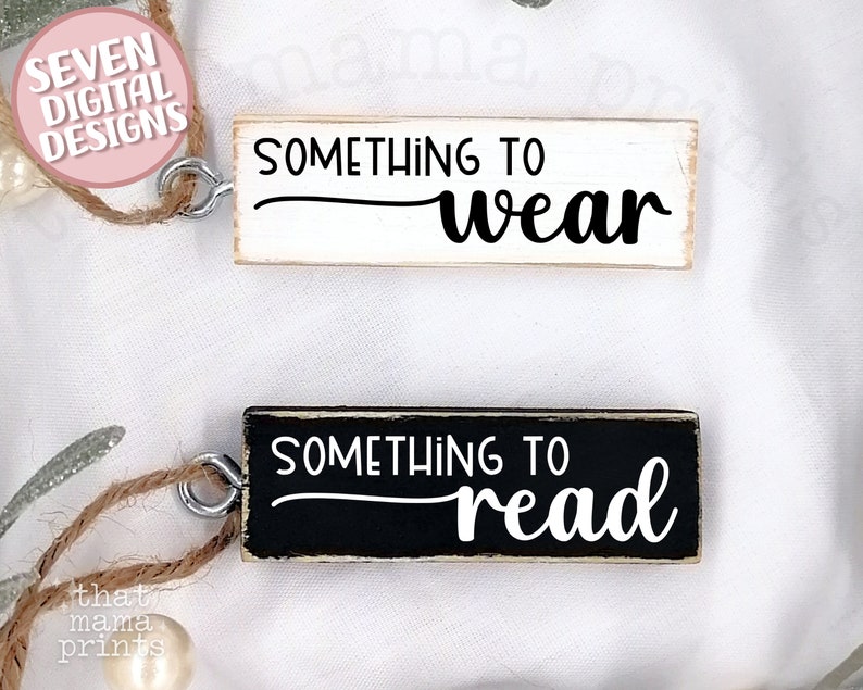 May include: Two wooden signs with black text. The top sign is white with the text "Something to wear". The bottom sign is black with the text "Something to read".