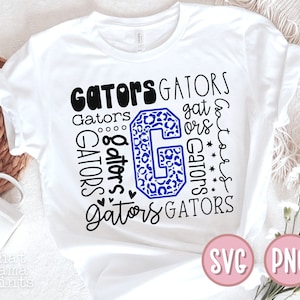 Peut inclure: T-shirt blanc avec une lettre G en imprimé léopard bleu et noir entourée du mot "Gators" répété dans différentes polices et tailles. Le t-shirt affiche également les mots "SVG" et "PNG" dans des cercles roses en bas.