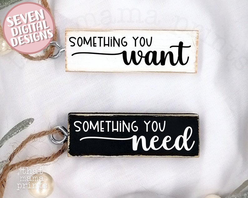 May include: Two wooden signs with black and white text. The top sign is white with black text that reads "Something you want". The bottom sign is black with white text that reads "Something you need".