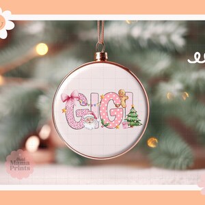 May include: A pink and white Christmas ornament with the name "GIGI" in a festive font. The ornament features a Santa Claus, a gingerbread man, a Christmas tree, and a gift box.
