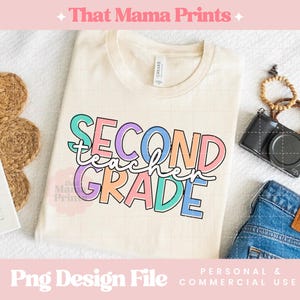 May include: Cream-colored t-shirt with the words "SECOND GRADE TEACHER" in colorful block letters. The shirt is folded and lies on a white surface, next to a pair of blue jeans, a camera, and a bracelet.