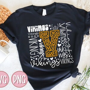 May include: Black t-shirt with a white graphic design of the letter "V" with a leopard print pattern. The graphic is surrounded by the word "Vikings" repeated in different sizes and styles.