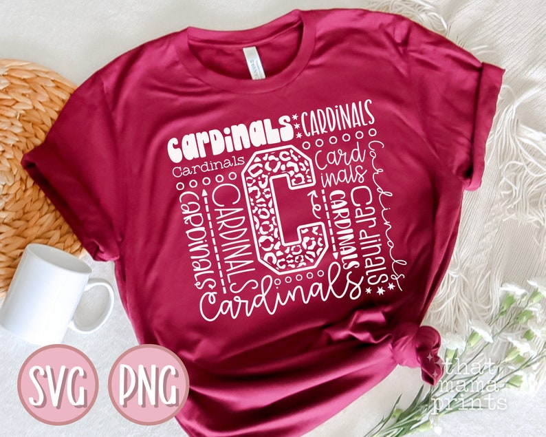 Pu&ograve; includere: Una maglietta color granata con un designo bianco che presenta la parola "Cardinals" ripetuta in diverse dimensioni e stili. Il design include anche una grande lettera "C" con uno schema leopardato.