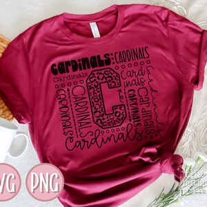 Pu&ograve; includere: Una maglietta color granata con un design grafico nero che presenta la parola "Cardinals" ripetuta in varie dimensioni e stili. Il grafico include anche una grande lettera "C" con uno stampa leopardato.
