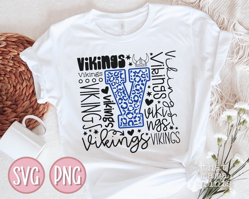 May include: White t-shirt with a blue and black leopard print "V" and the word "Vikings" repeated in different sizes and styles.