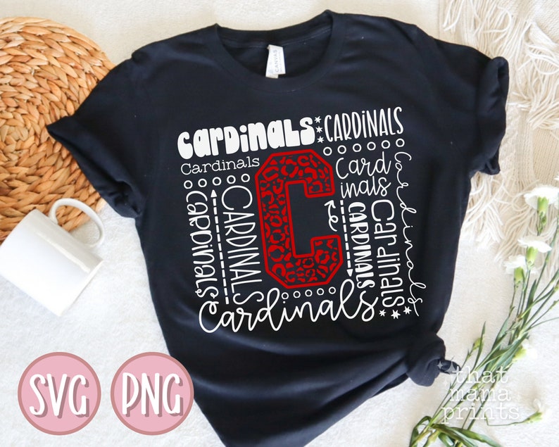 Pu&ograve; includere: Maglietta nera con un designo bianco che presenta la parola "Cardinals" ripetuta in diverse dimensioni e stili. Una grande "C" rossa con un motivo a stampa leopardata si trova al centro del design.