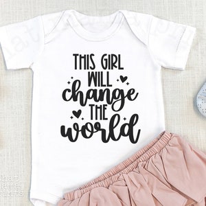 May include: White baby onesie with black text that reads "This girl will change the world".