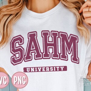 May include: White t-shirt with a maroon graphic that says "SAHM UNIVERSITY".