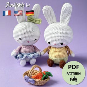 Peut inclure: Deux poupées lapins crochetées blanches avec des tenues roses et bleues, se tenant la main, et un petit panier avec des carottes. L'image comprend le texte "PDF PATTERN only" et "Available in" avec des drapeaux.