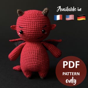 Peut inclure: Une poupée diable rouge au crochet faite à la main avec de petites cornes, des ailes et une queue. La poupée a une expression mignonne et est étiquetée "PDF PATTERN only". L'image comprend également les drapeaux de la France, des États-Unis et de l'Allemagne, avec le texte "Available in".