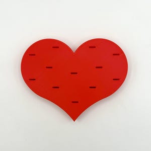 May include: A red heart-shaped wall organizer with multiple slots for holding small items.