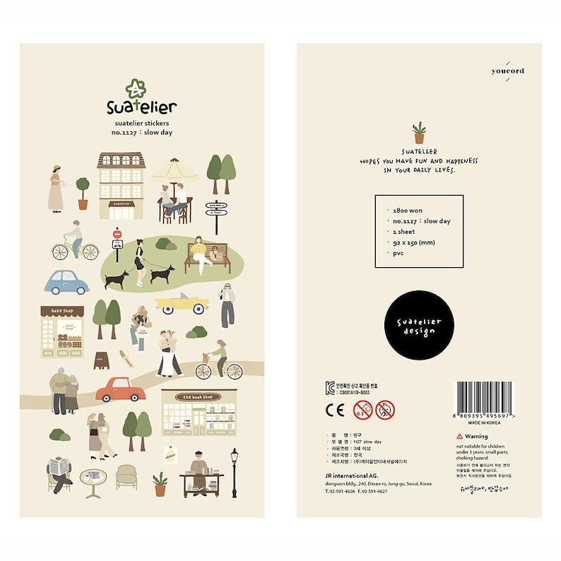 May include: Two-sided sticker sheet with a beige background. One side features a town scene with illustrations of people, buildings, and vehicles. The other side has text, including "Suatelier" and "slow day," along with product details and a warning.