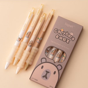 Könnte beinhalten: Ein Set aus vier mechanischen Bleistiften zum Thema Capybara in einer Box. Die Stifte sind cremefarben und braun mit einer Capybara-Illustration. Die Box ist hellbraun mit dem Text "Capybara" und "lopet". Die Stifte sind 0,5 mm.