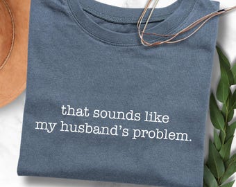 May include: A blue t-shirt with the text "that sounds like my husband's problem." printed in white.