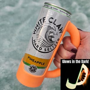 May include: A can of White Claw Hard Seltzer in a bright orange holder. The can is silver with black and white branding and a pineapple flavor label. The holder has a handle and glows in the dark.