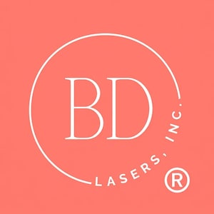 May include: A logo featuring the white capital letters "BD" inside a white circle, set against a coral background. The words "LASERS, INC." are written in white around the circle's perimeter, with a registered trademark symbol.
