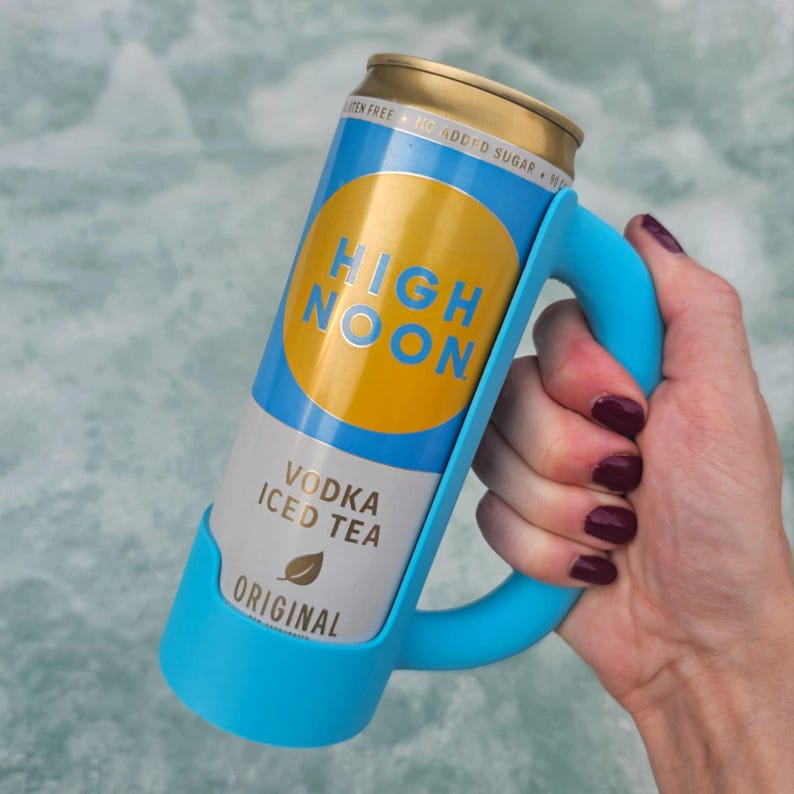 May include: A can of High Noon Vodka Iced Tea in a blue holder. The can has a gold top and a label with the words "HIGH NOON" in yellow and blue. The holder has a handle for easy carrying.