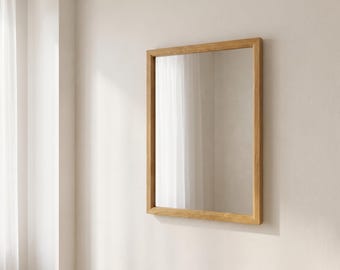 Könnte beinhalten: Ein rechteckiger Wandspiegel mit einem hellbraunen Holzrahmen in glatter Ausführung. Das Spiegelglas ist klar und reflektierend und zeigt einen neutralen Farbton. Der Rahmen hat gerade Kanten und eine einfache, klare Konstruktion.