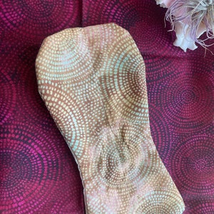 May include: A brown fabric pouch with a light blue and white circular pattern. The pouch is sewn with a white thread and has a slightly pointed shape.