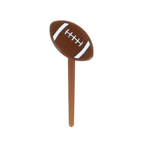 May include: Brown and white football cupcake topper. The football is on a brown stick.