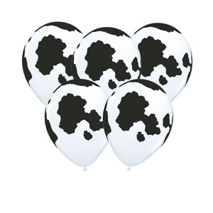 May include: A set of five black and white cow print latex balloons. The balloons are inflated and ready to be used for a party or celebration.