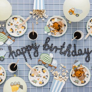 K&ouml;nnte beinhalten: Eine festliche Geburtstagsfeier mit Tellern, Bechern und Dekorationen. Mit dem Thema Baufahrzeuge, die Teller zeigen LKW-Designs. Ein "Happy Birthday" Banner und Popcorn vervollst&auml;ndigen die Feier.