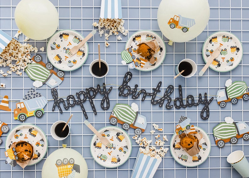 K&ouml;nnte beinhalten: Eine festliche Geburtstagsfeier mit Tellern, Bechern und Dekorationen. Mit dem Thema Baufahrzeuge, die Teller zeigen LKW-Designs. Ein "Happy Birthday" Banner und Popcorn vervollst&auml;ndigen die Feier.