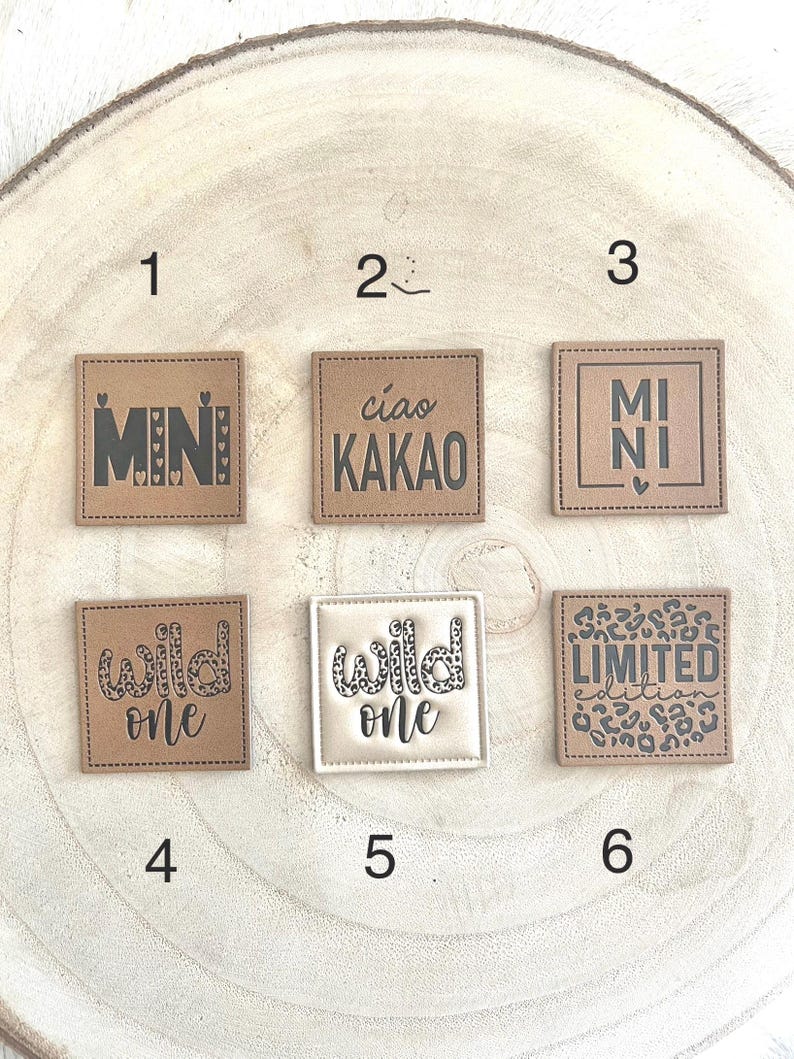 Pode incluir: Uma cole&ccedil;&atilde;o de seis patches quadrados com v&aacute;rios designs e texto. Os patches s&atilde;o em tons neutros de castanho e branco. O texto inclui "MINI", "ciao KAKAO", "MI NI", "wild one" e "LIMITED edition".