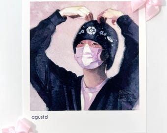 May include: Watercolour painting of a person wearing a black beanie with white floral designs, a pink and white face mask, and a black jacket. The painting is on a white background with the text "agustd" at the bottom.