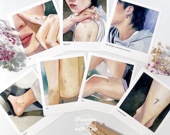 May include: A collection of seven watercolor art prints on white polaroid-style cards. Each print features a body part with the number "7" tattooed on it. The prints are arranged on a white surface with dried flowers.